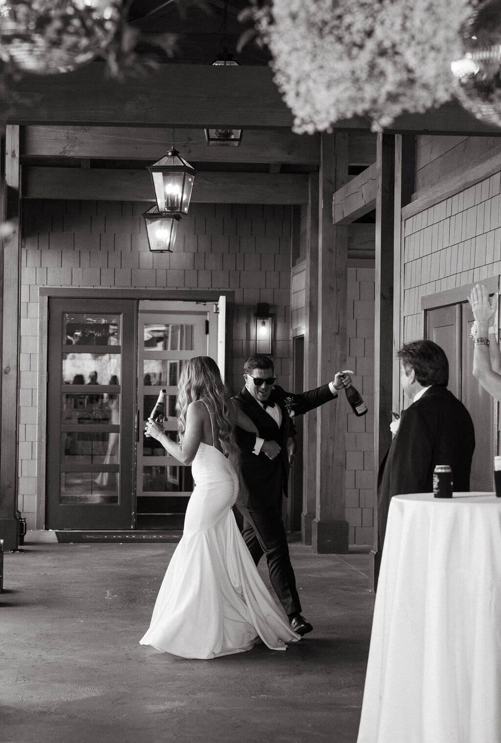 Black and white photo of bride and groom entering wedding reception