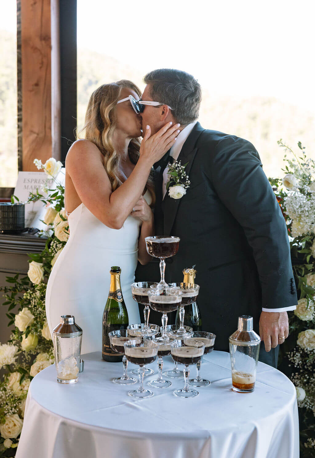 Bride and groom kissing while wearing sunglasses during wedding reception