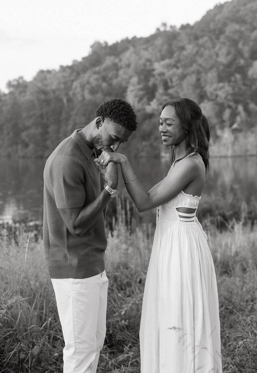 Black and white engagement photo near Knoxville, Tennessee featuring the couple laughing together in a grassy field.