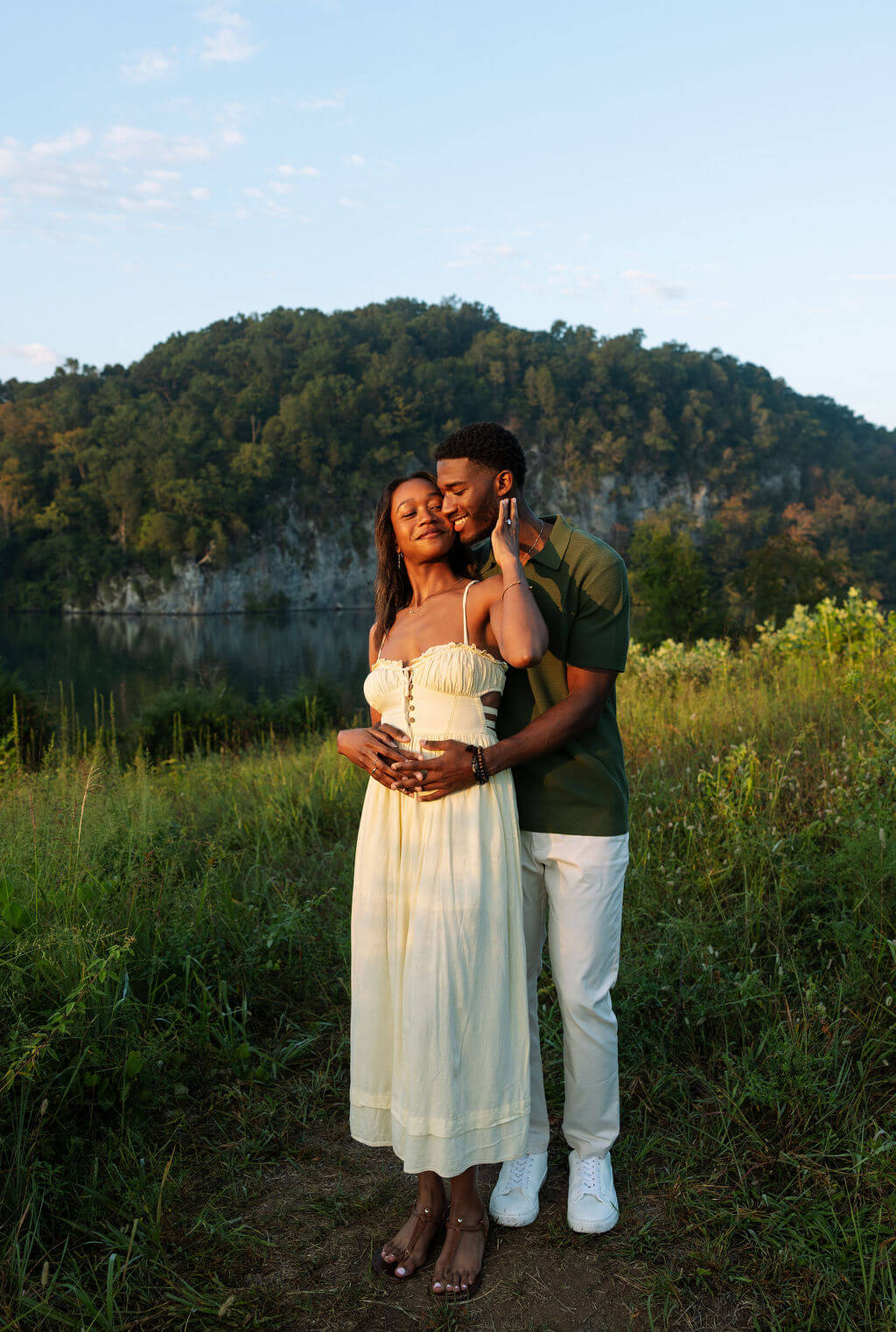 Romantic engagement portrait near the lake in Knoxville, Tennessee featuring the couple embracing during golden hour.