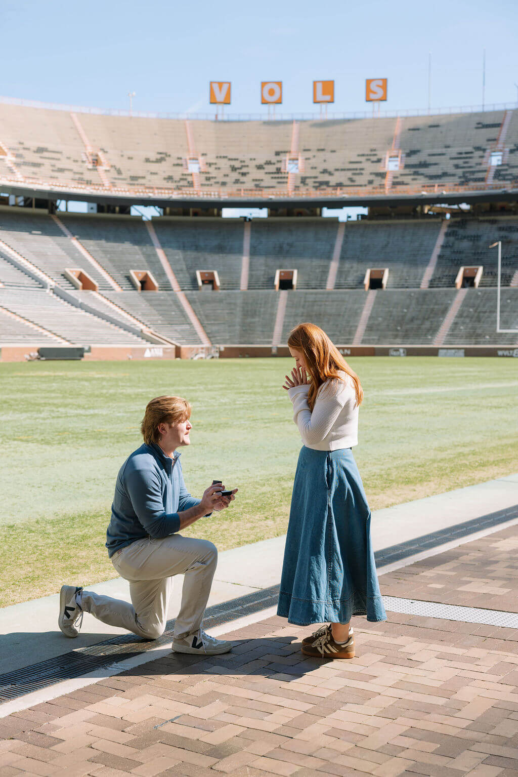 Proposal at Neyland Stadium in Knoxville, Tennessee featuring the groom kneeling on the football field.