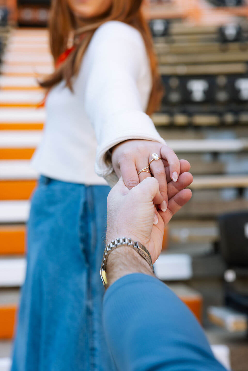 Close-up engagement photo at Neyland Stadium in Knoxville, Tennessee featuring the couple holding hands and showing the engagement ring.