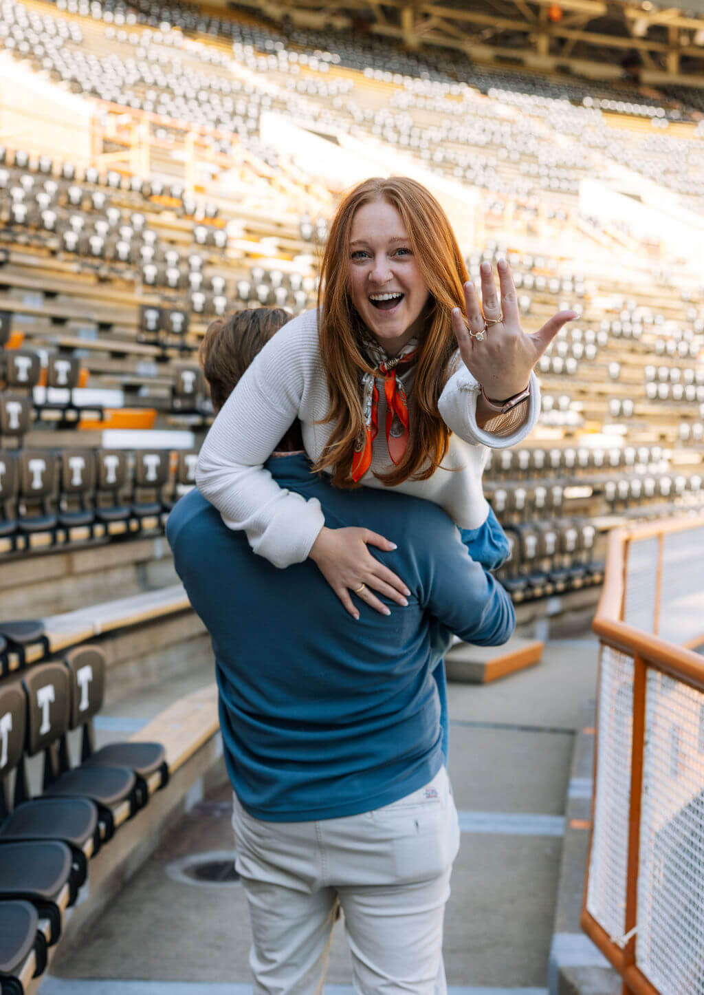 Celebration photo after a proposal at Neyland Stadium in Knoxville, Tennessee featuring the couple hugging in the stands.