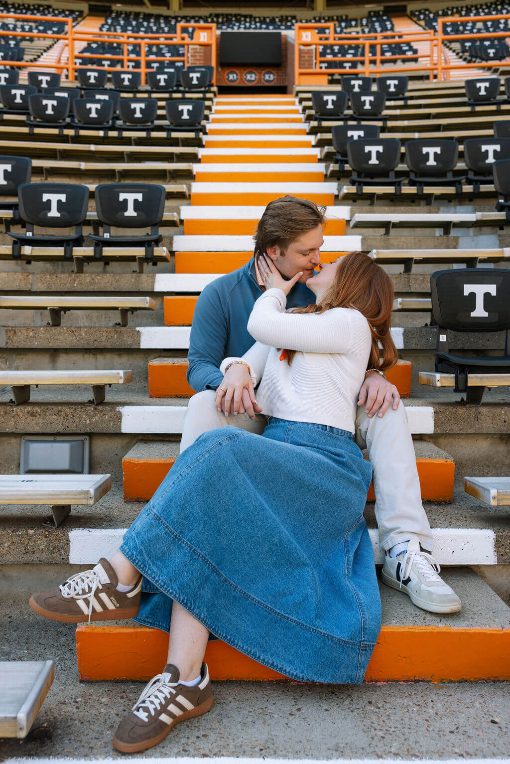 Couple sitting together in the stadium seats during a Knoxville, Tennessee engagement session at Neyland Stadium.