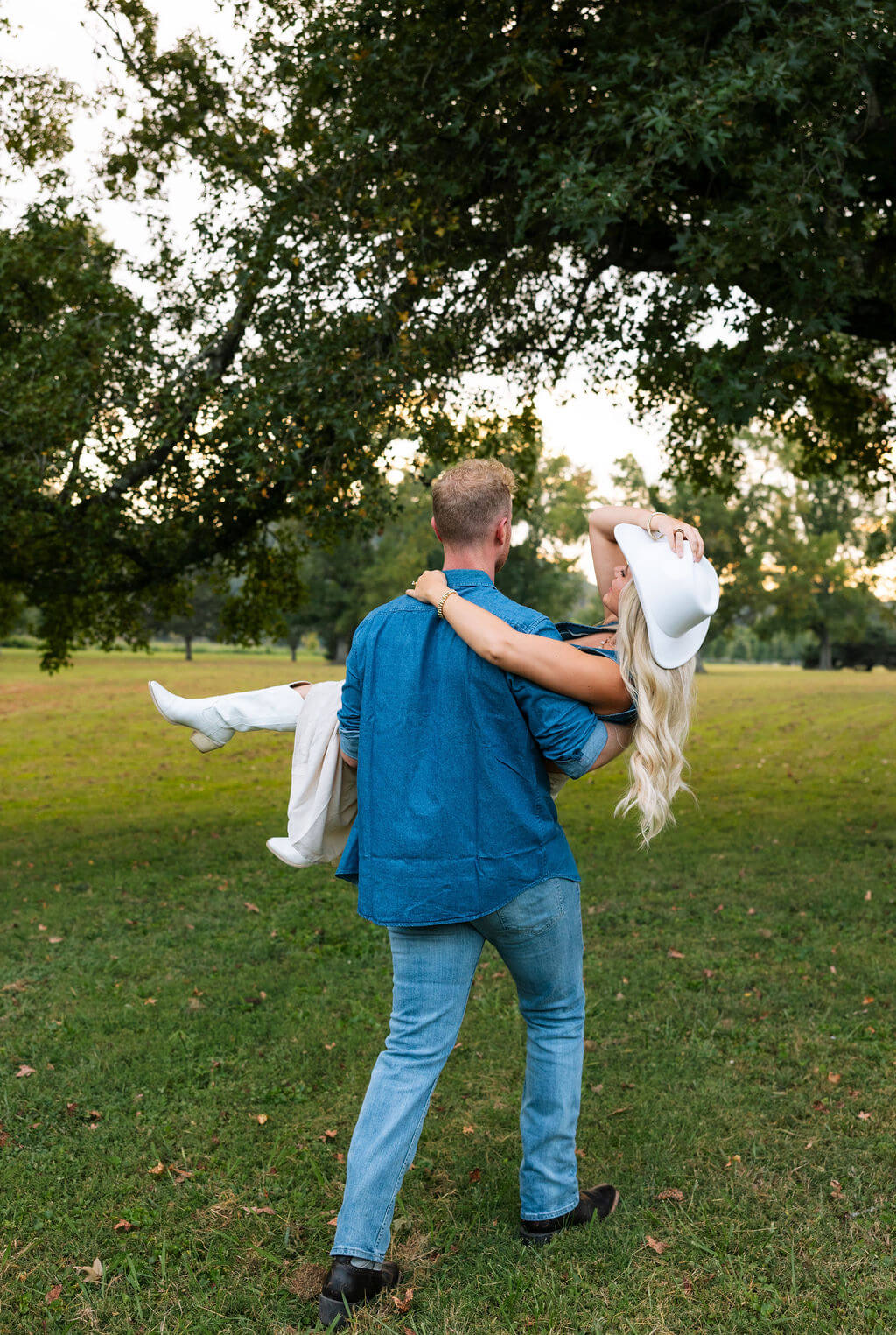 Couple walking through a grassy field during a Knoxville, Tennessee engagement session at golden hour.