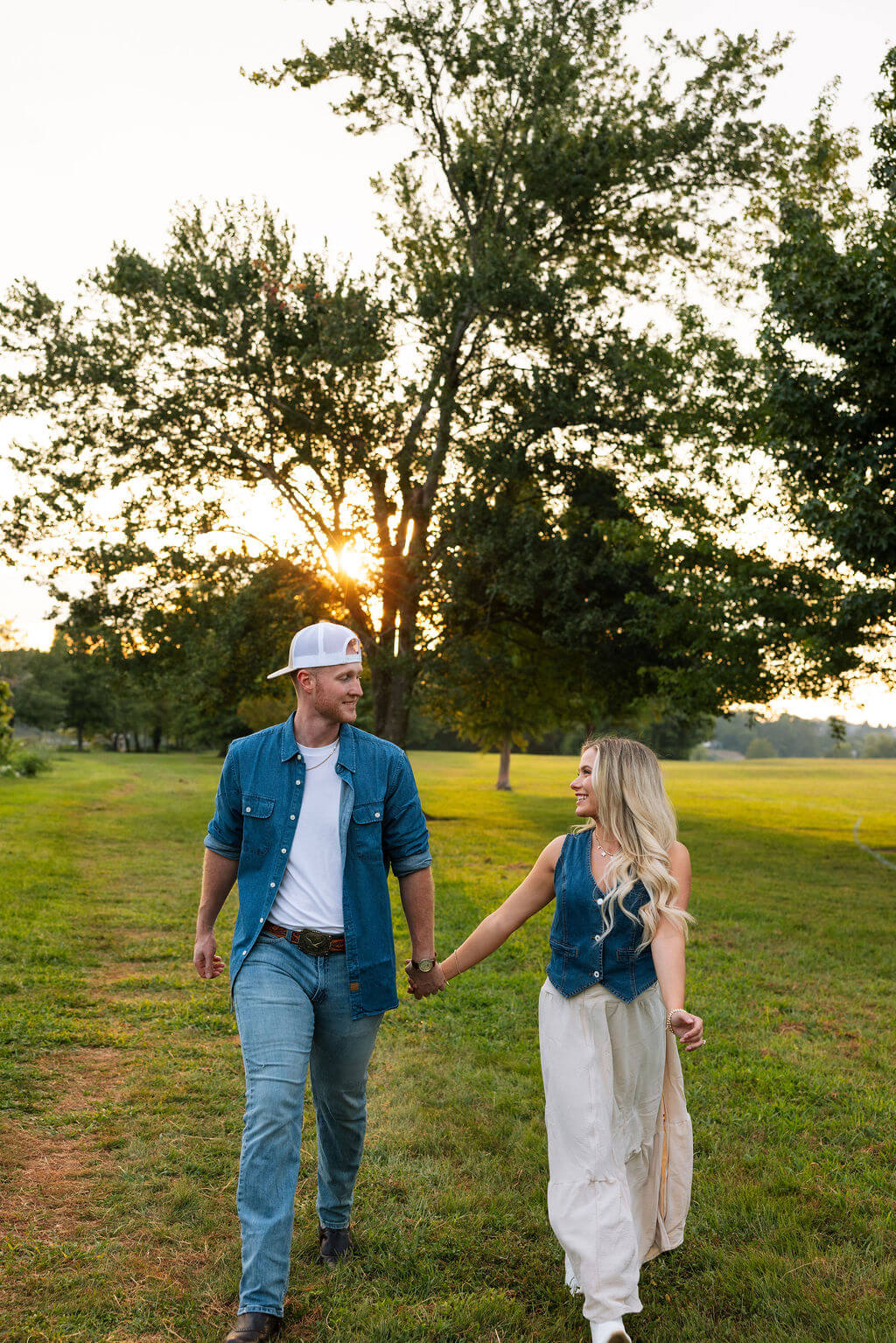 Couple holding hands and walking together during a Knoxville, Tennessee engagement photo session at sunset.