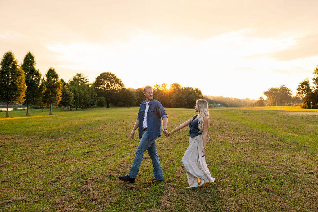 Couple walking through a field during sunset in Knoxville, Tennessee during an engagement session.