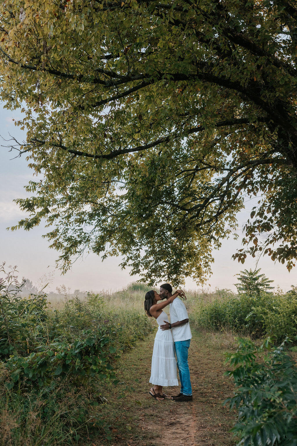 Romantic engagement photo beneath a large tree during a Knoxville, Tennessee couples session near the water.