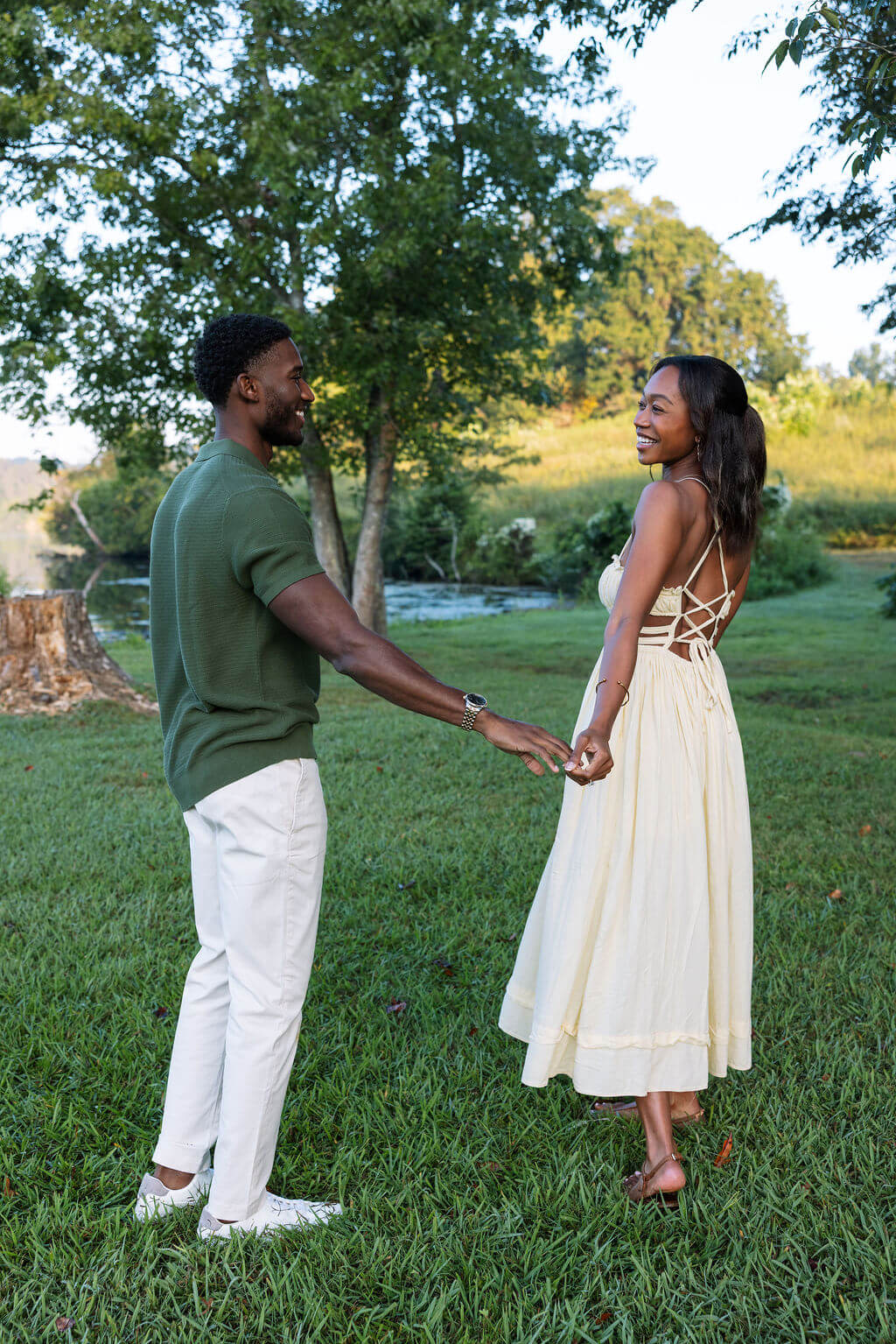 Couple holding hands and smiling during a Knoxville, Tennessee engagement session in a grassy field.