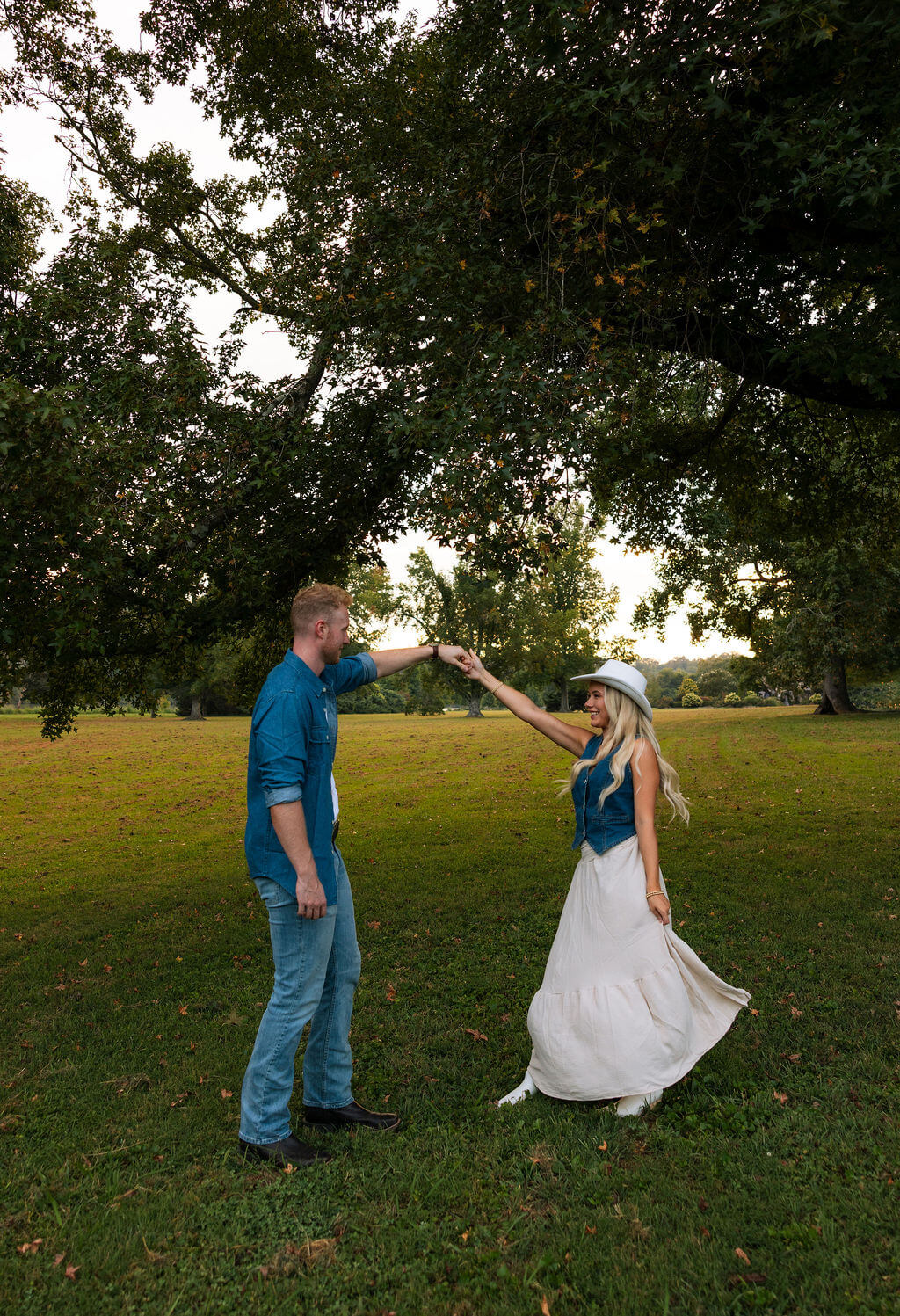 Couple twirling together in a field during a Knoxville, Tennessee engagement session at golden hour.