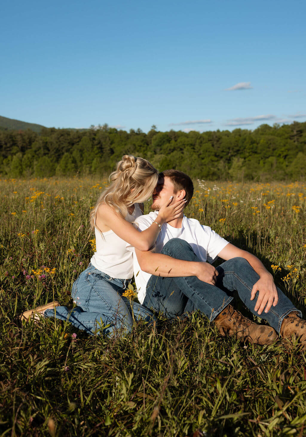 Couple sitting together in a wildflower field during a Knoxville, Tennessee engagement session at sunset.