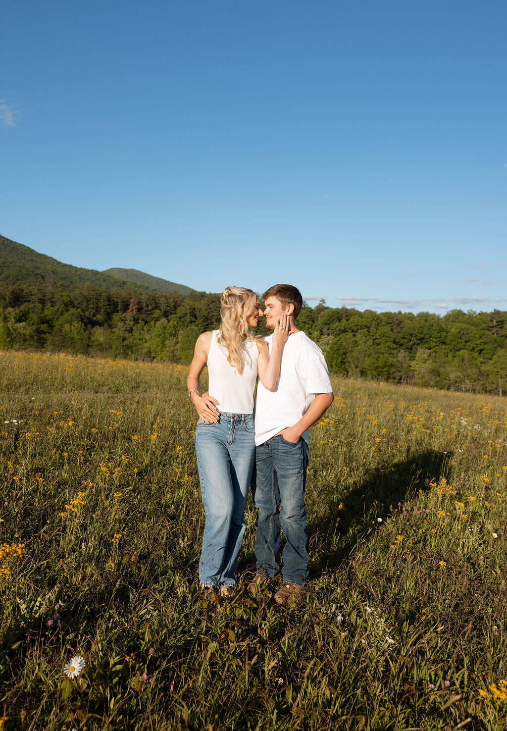 Couple standing in a wildflower field with mountain views during a Knoxville, Tennessee engagement session.