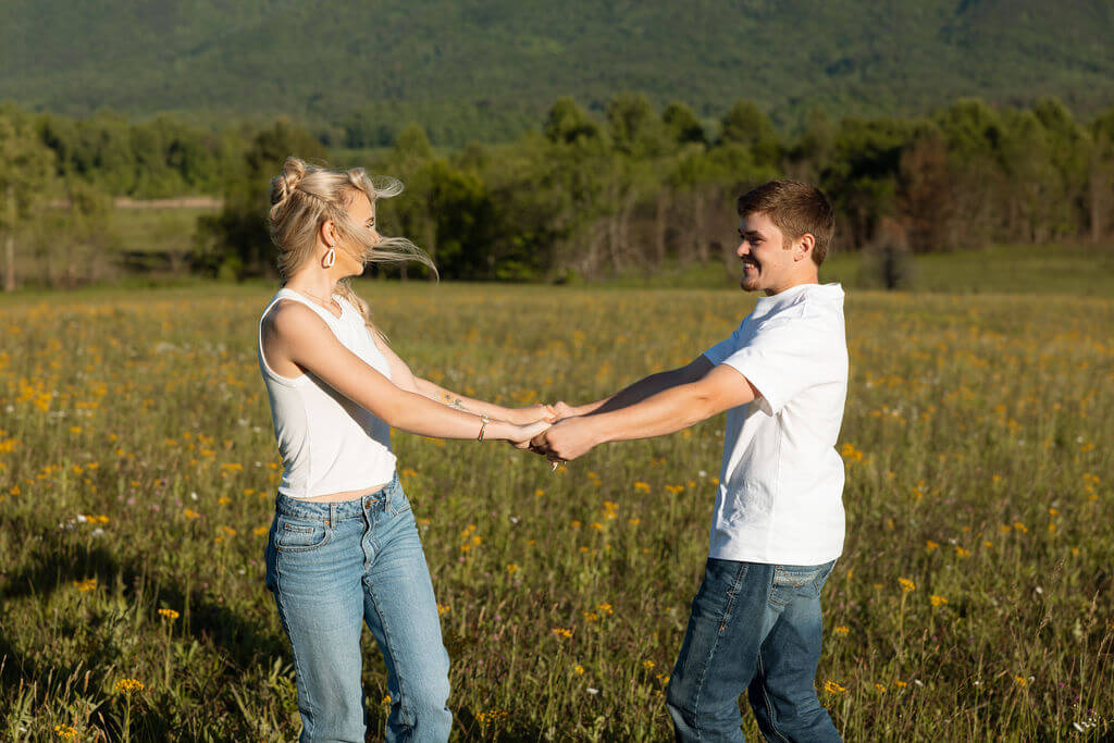Couple holding hands in a wildflower field with mountain views during a Knoxville, Tennessee engagement session.
