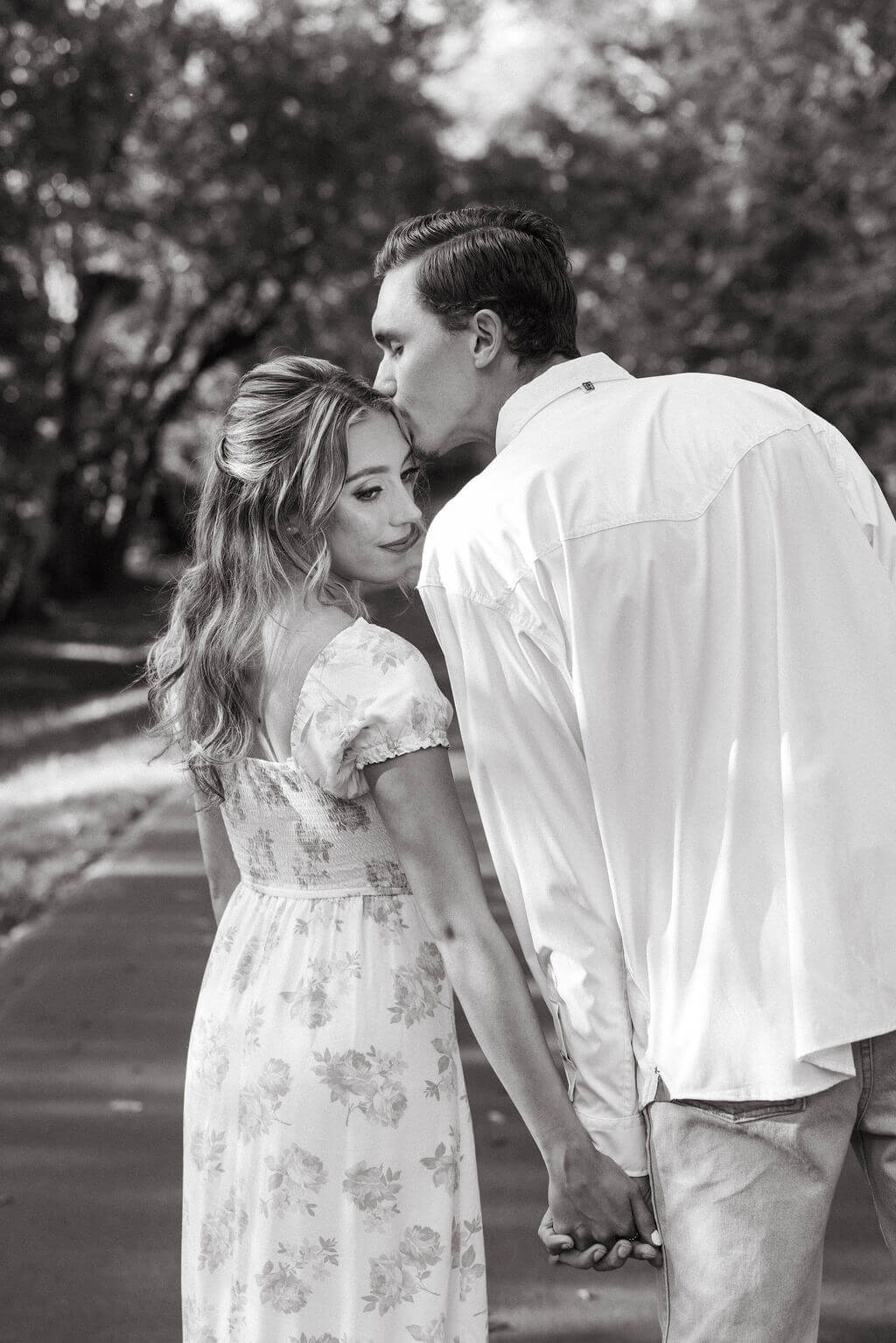 Black and white engagement portraits at Maple Grove Estate with couple walking hand in hand