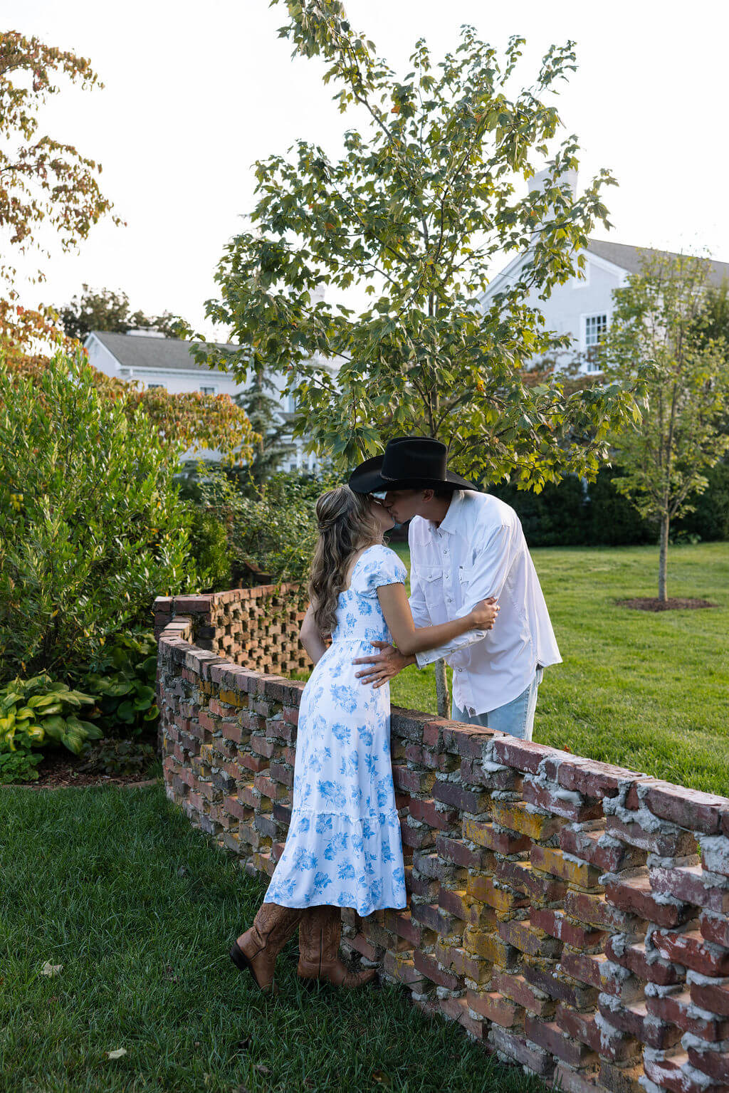 Couple kissing over a brick wall during a Maple Grove Estate engagement session