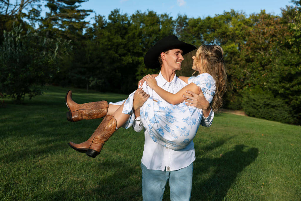 Western inspired engagement portraits at Maple Grove Estate with groom carrying bride across an open field