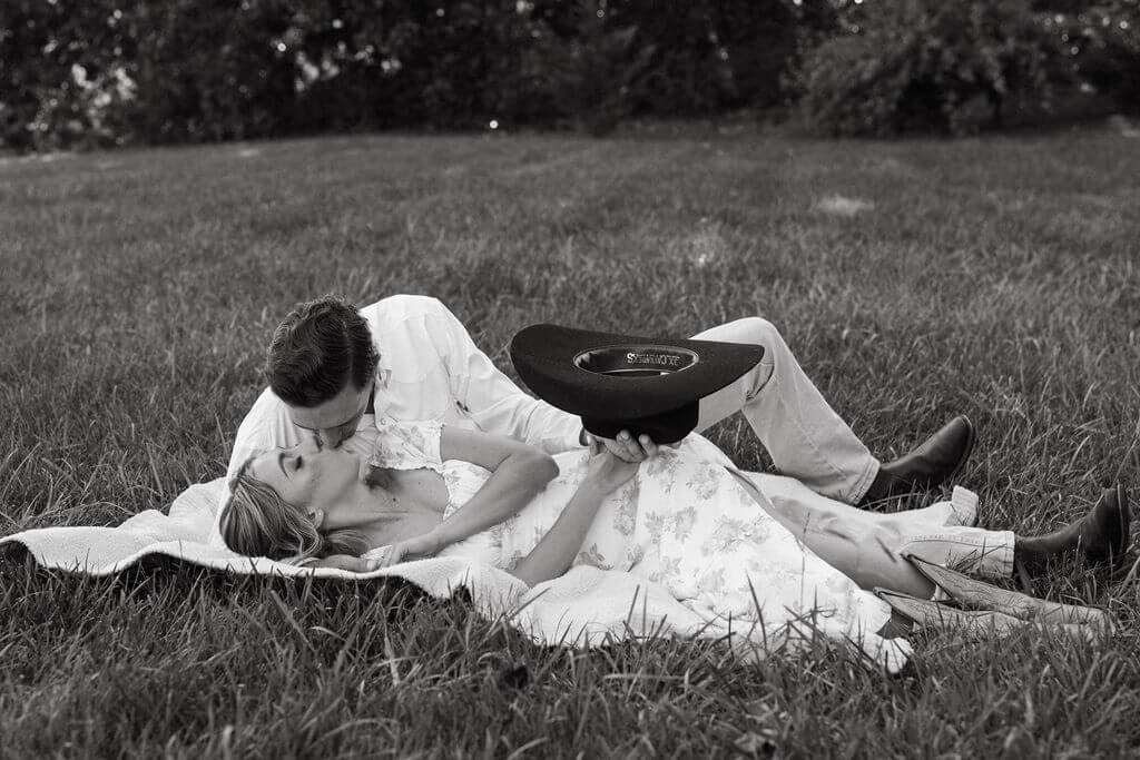 Black and white engagement photos at Maple Grove Estate with couple lying together in the grass