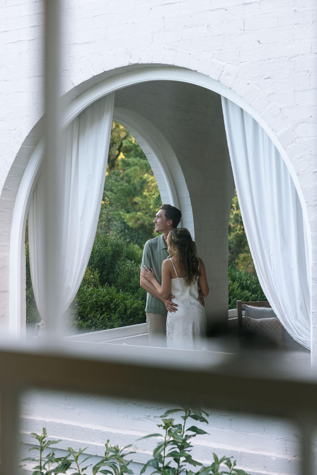 Elegant engagement portraits through white arched windows at Maple Grove Estate