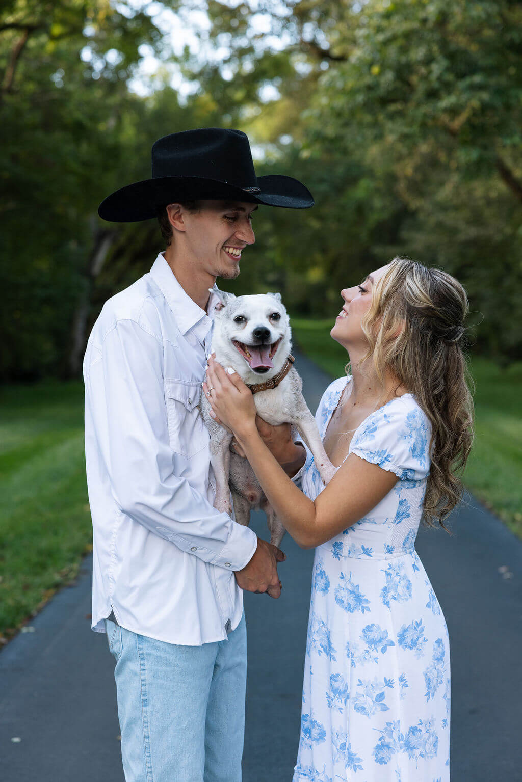Playful engagement portraits at Maple Grove Estate with couple and their dog smiling together