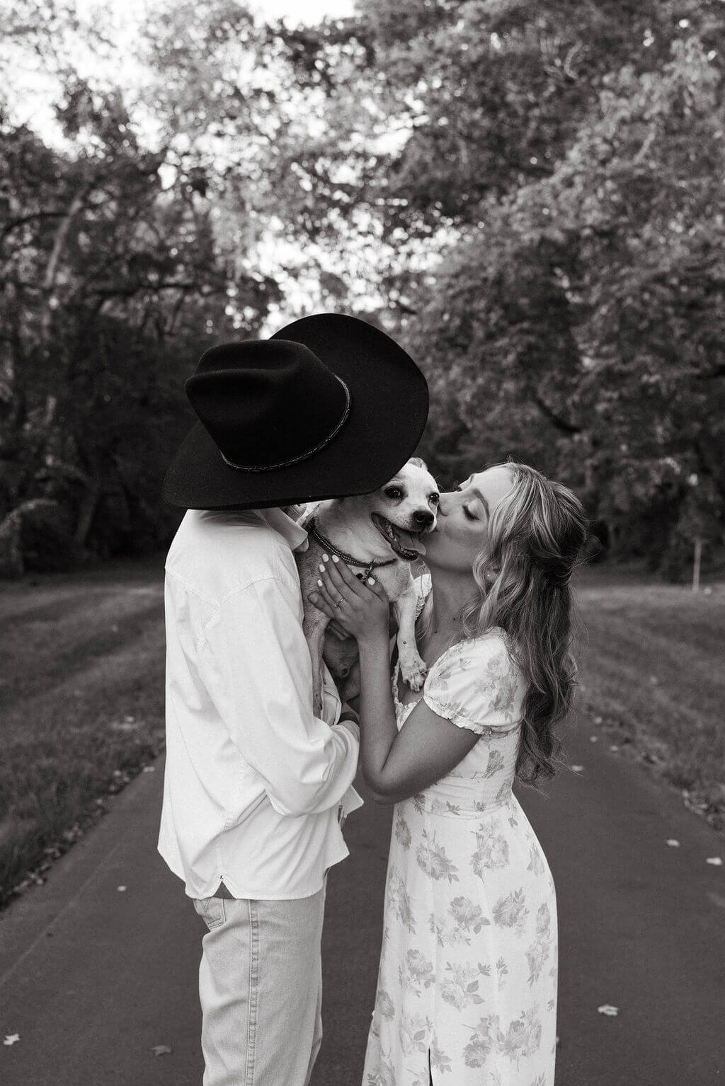 Black and white engagement portraits with couple kissing and holding their dog at Maple Grove Estate