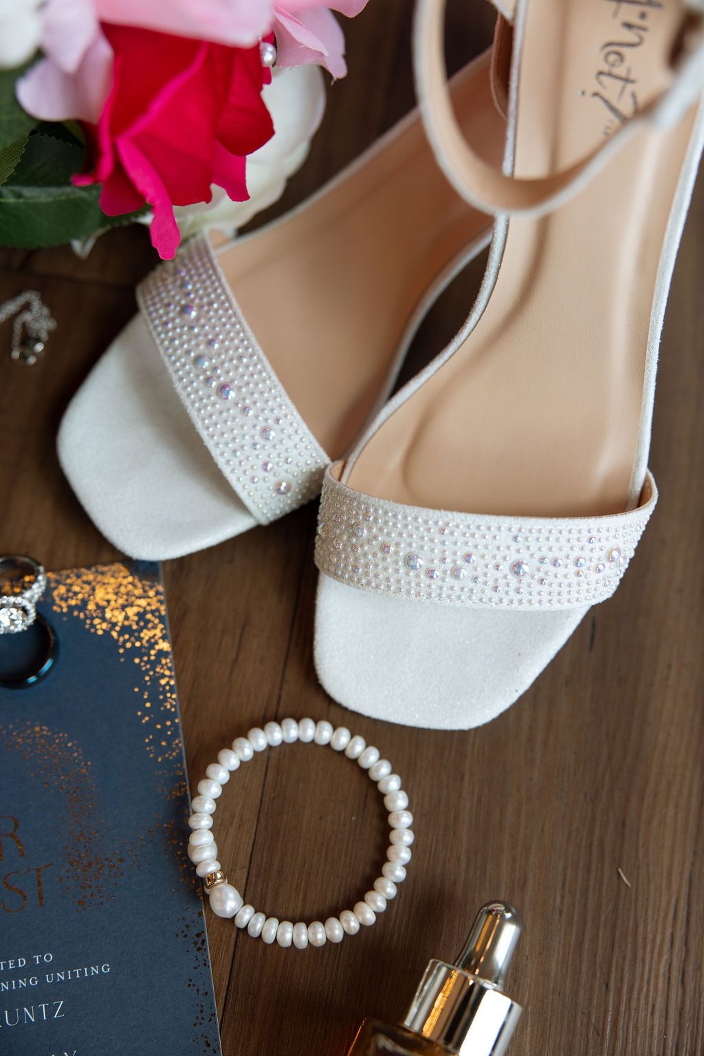 Bridal shoes with pearl details styled alongside wedding invitations and jewelry details