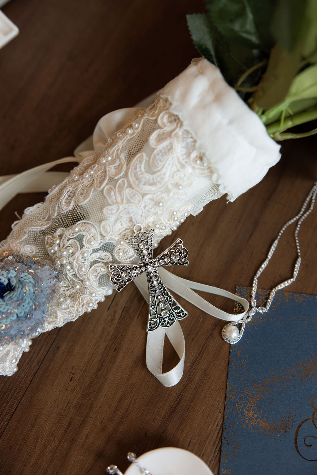 Wedding day details including lace garter, cross charm, and jewelry photographed at a Sevierville wedding venue