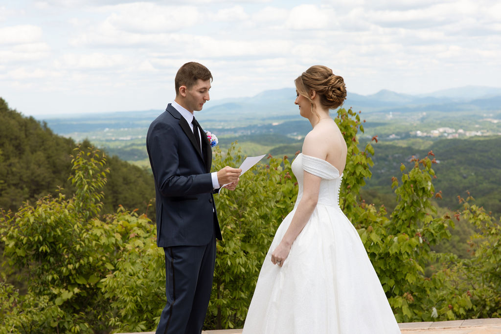 Bride and groom reading private vows together with panoramic mountain views behind them