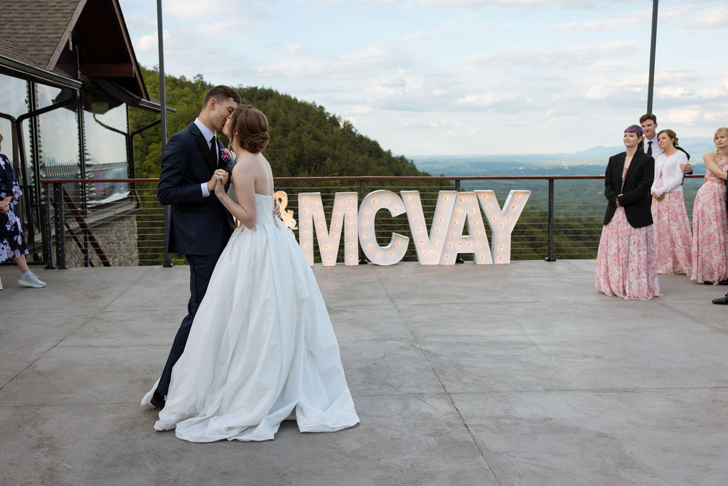 Couple sharing their first dance outdoors with Smoky Mountain views behind them at a Sevierville wedding venue