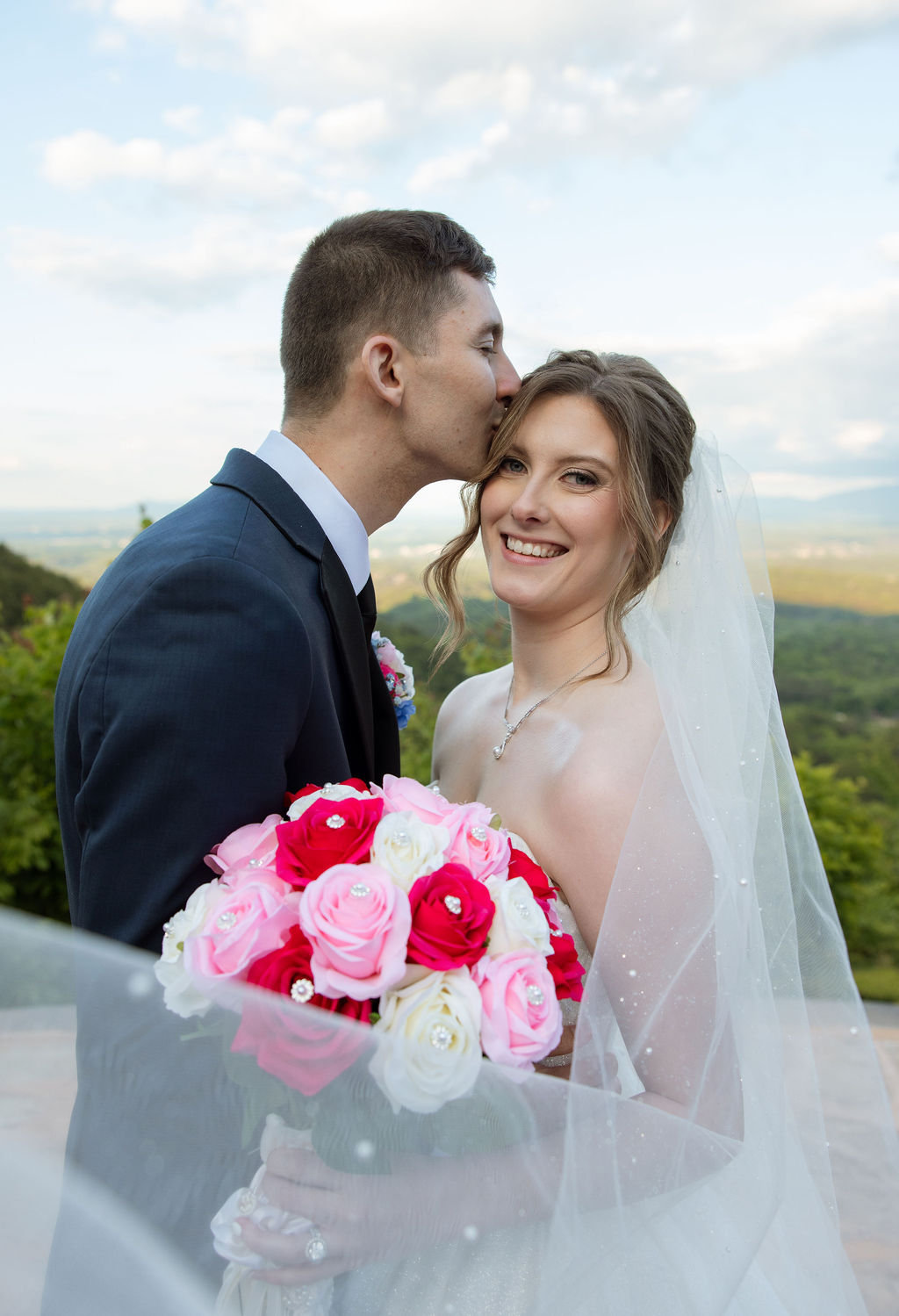 Romantic wedding portrait of bride and groom with veil details and mountain scenery in the background