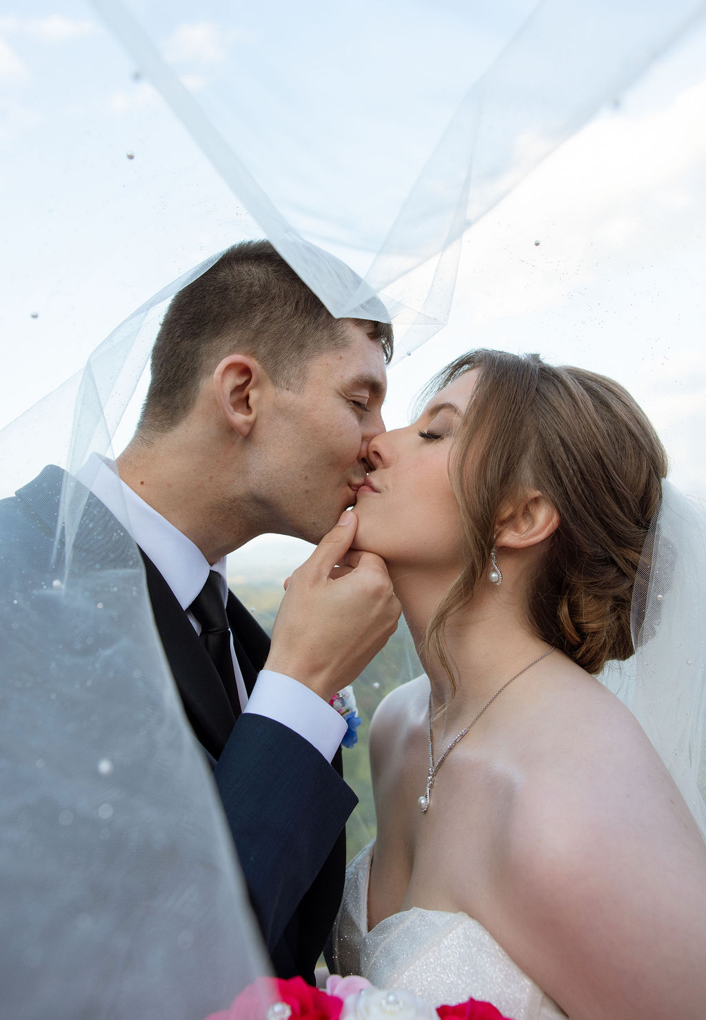 Close up wedding portrait of bride and groom kissing beneath a flowing veil during their mountain wedding day