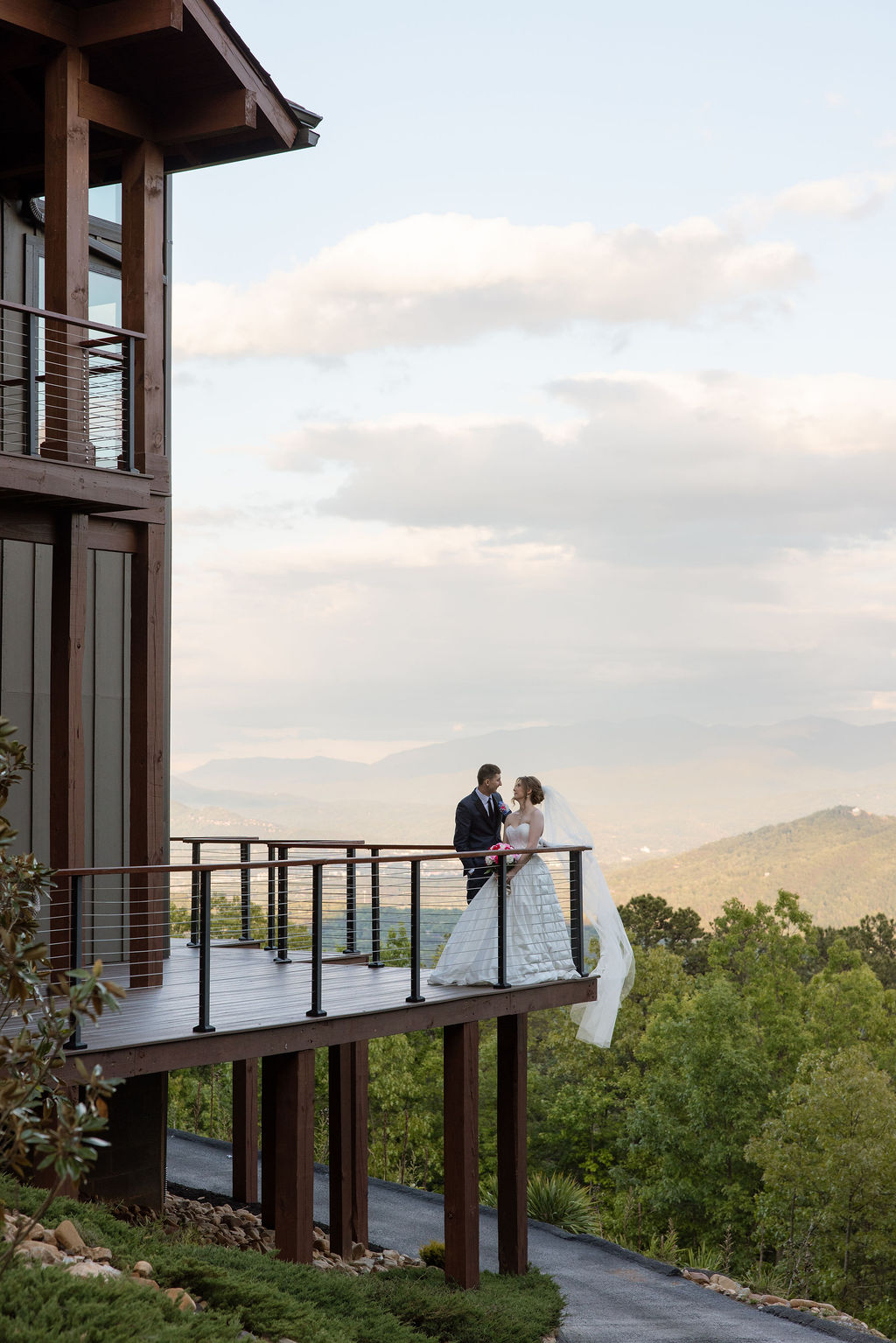 Newlyweds standing together on a balcony overlooking the Smoky Mountains during sunset portraits