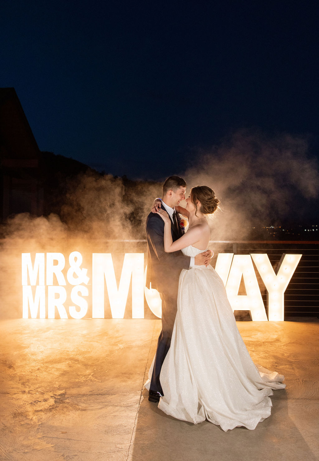 Romantic nighttime portrait of newlyweds in front of illuminated marquee letters at a Sevierville wedding venue