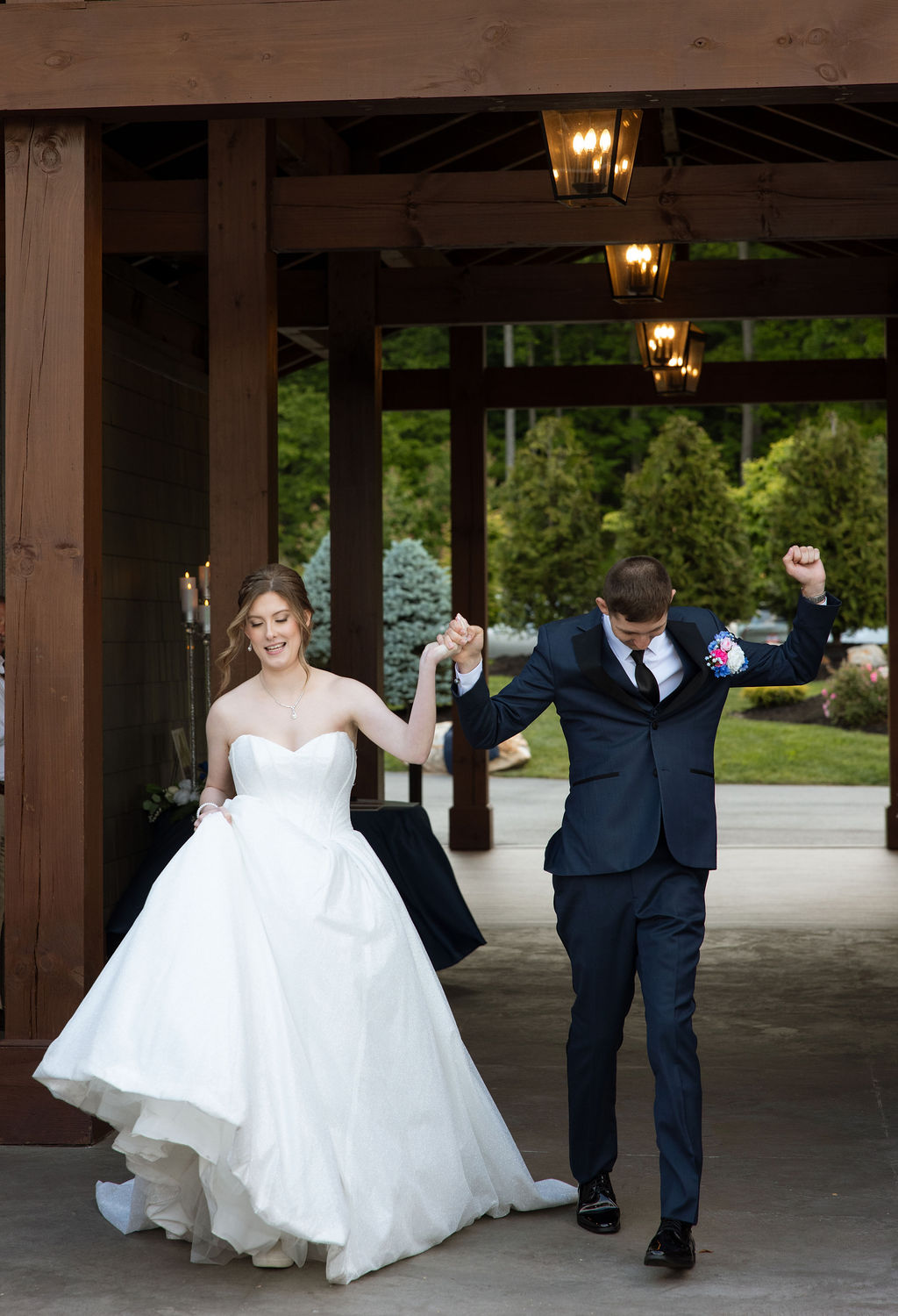Bride and groom walking hand in hand beneath wooden covered walkways at their mountain wedding venue in Tennessee