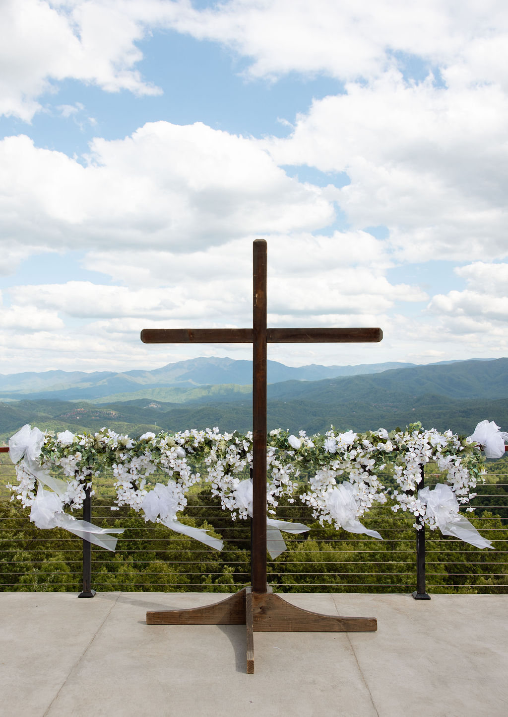 Wooden ceremony cross decorated with white florals overlooking the Smoky Mountains at a Sevierville wedding venue