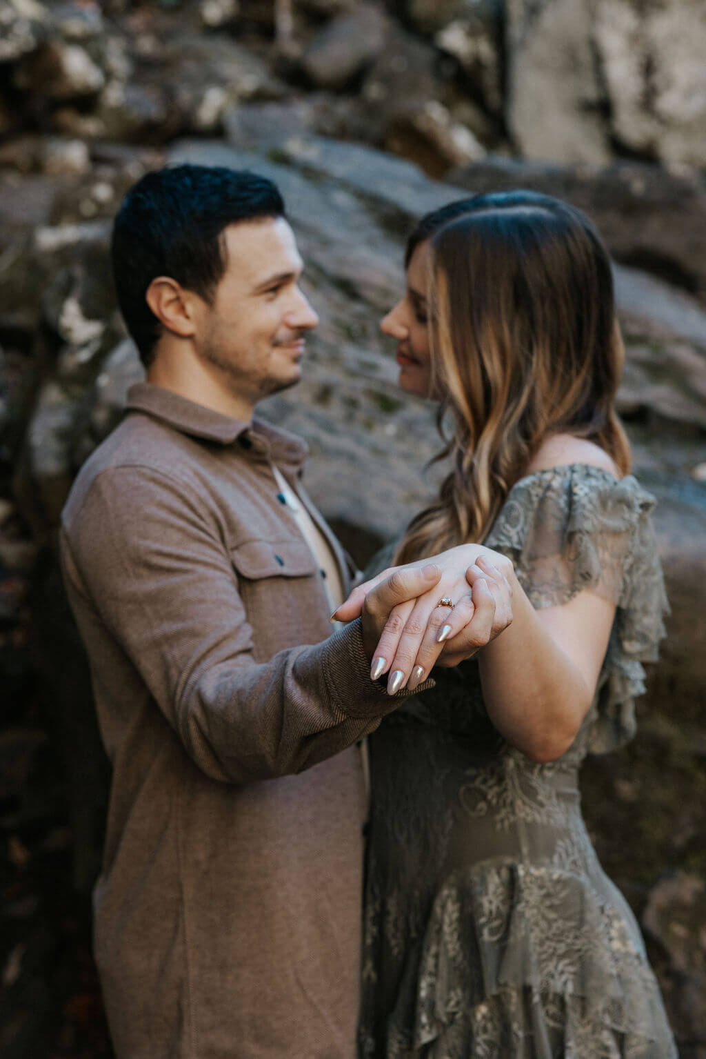 Couple holding hands on a rocky trail during fall engagement photos at a Tennessee waterfall location.