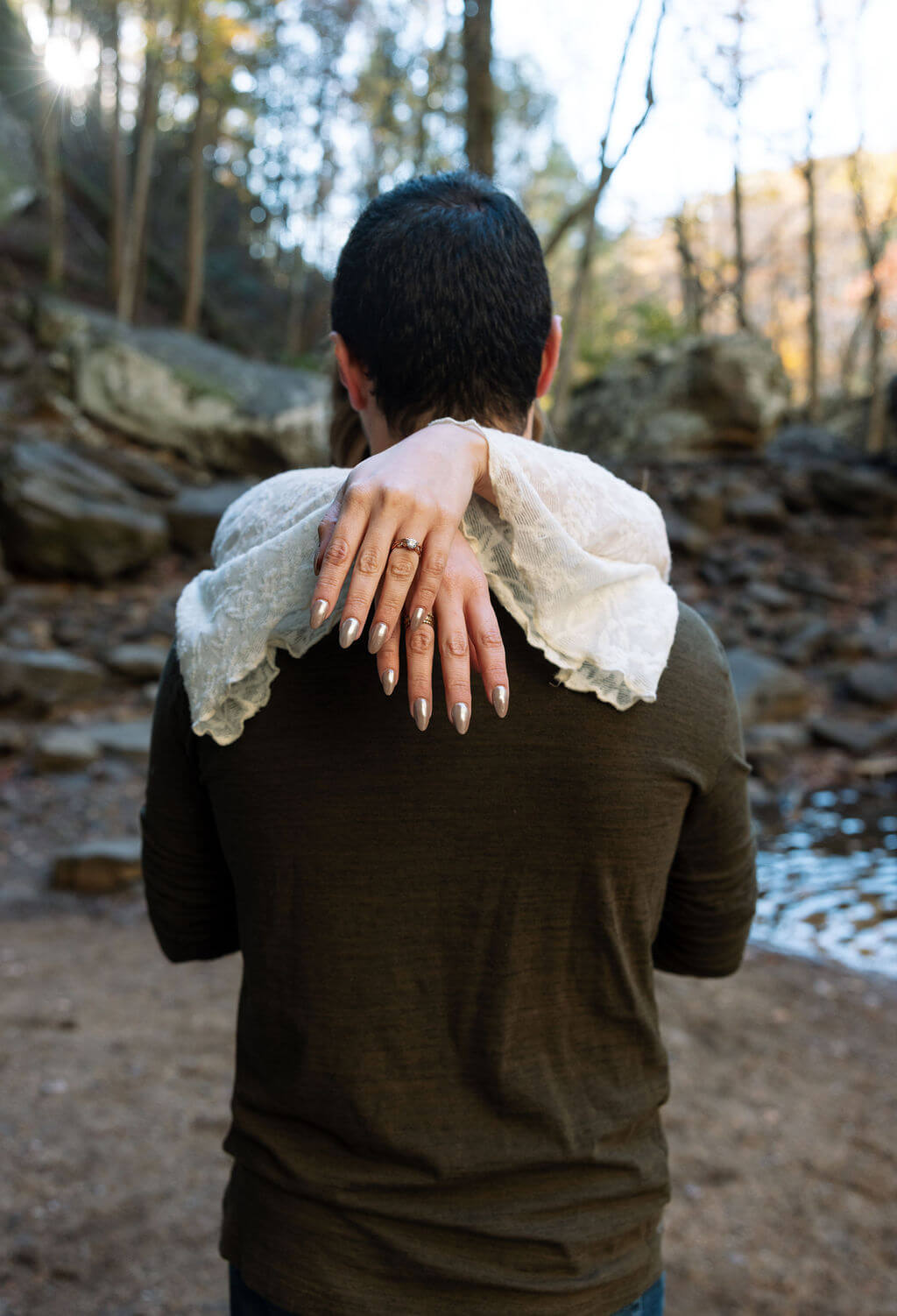 Close-up of a couple cuddling during fall engagement photos with the focus on her engagement ring.
