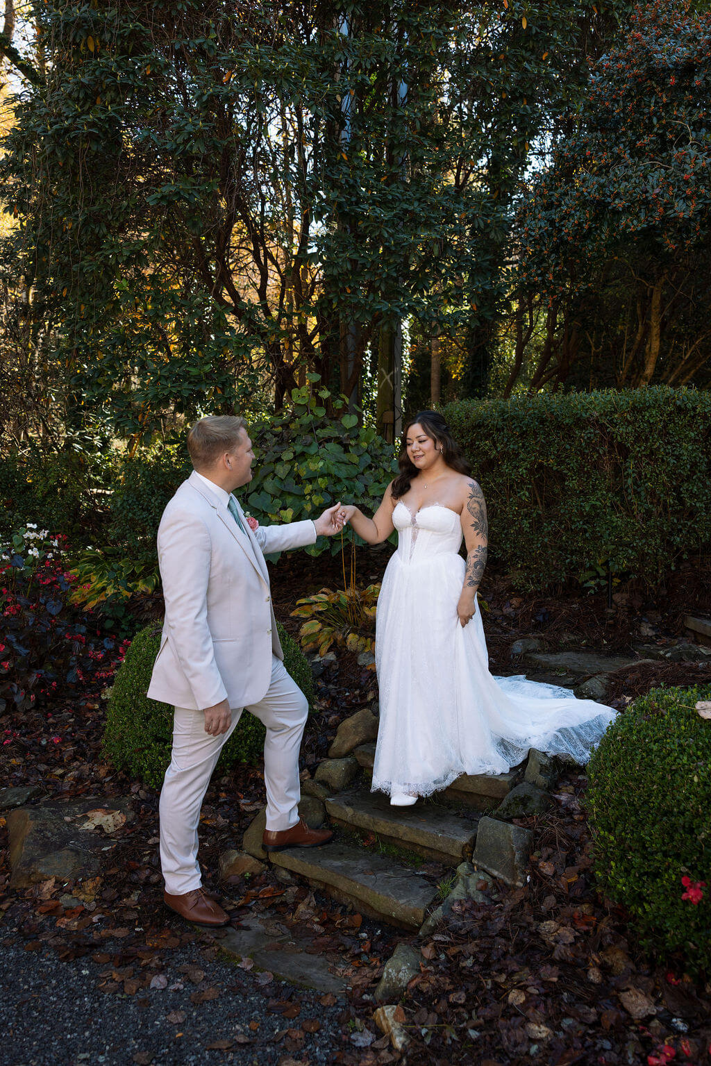 Partner twirls the bride on stone steps surrounded by lush gardens and autumn foliage.