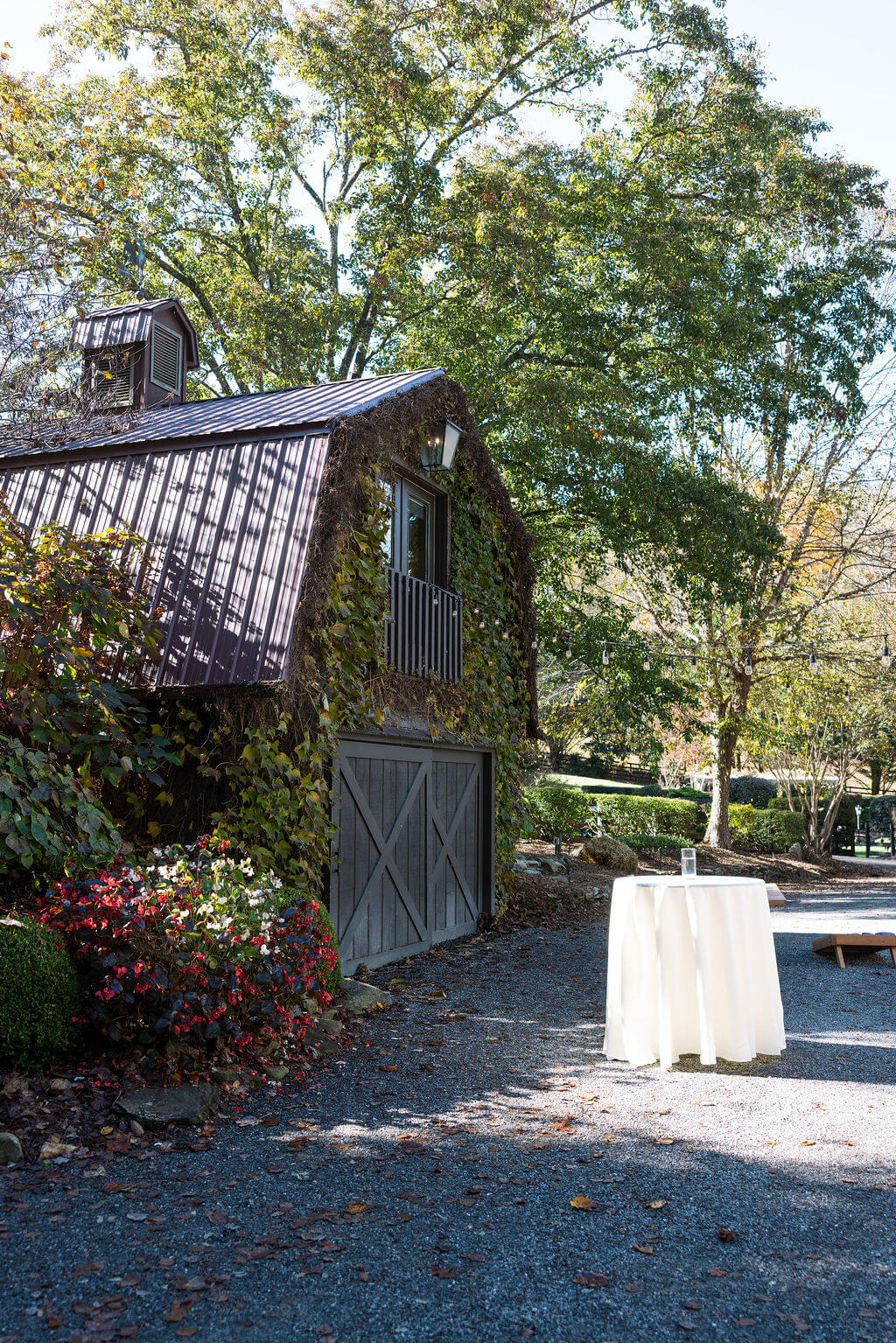Rustic barn and cocktail table surrounded by gardens at an intimate Tennessee fall wedding venue.