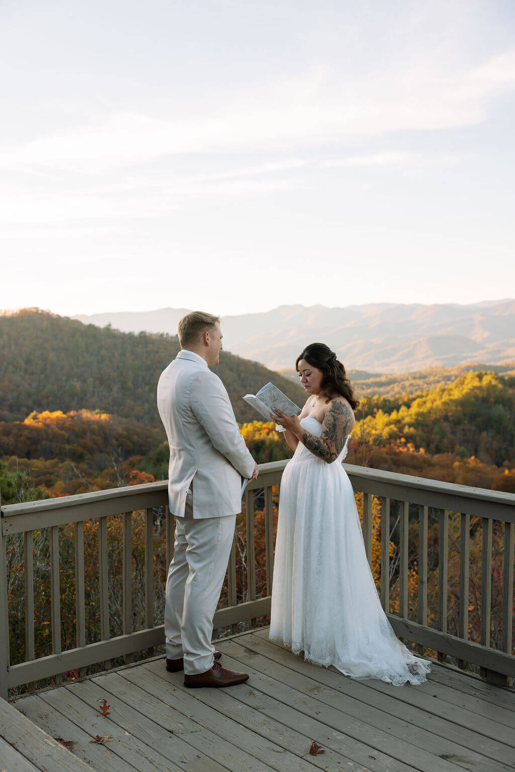 Bride reads private vows to her partner on a wooden deck overlooking the colorful Tennessee mountains.