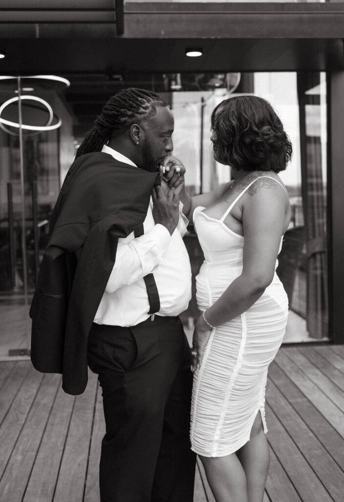 Black-and-white engagement photo of a formally dressed couple standing close together on a modern patio outside a Knoxville bar.