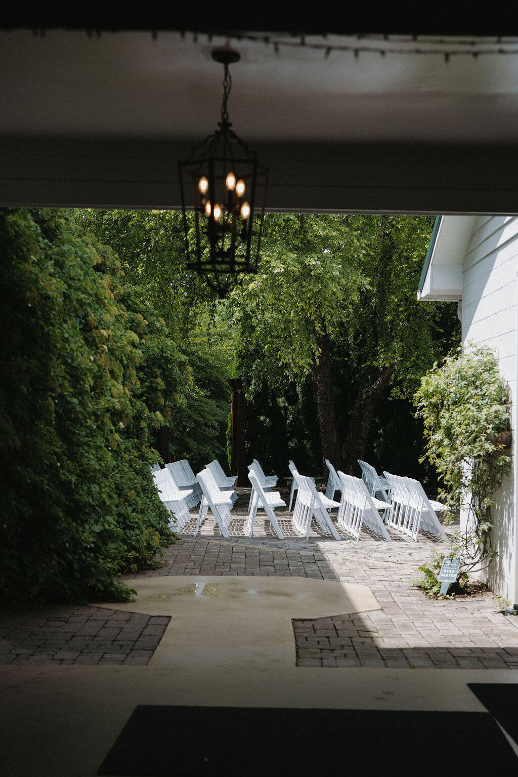 Outdoor wedding ceremony seating arranged along a stone aisle beneath a covered entrance.