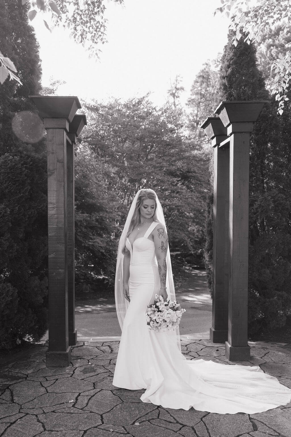 Black-and-white bridal portrait beneath a wooden garden arch at a Tennessee wedding venue.