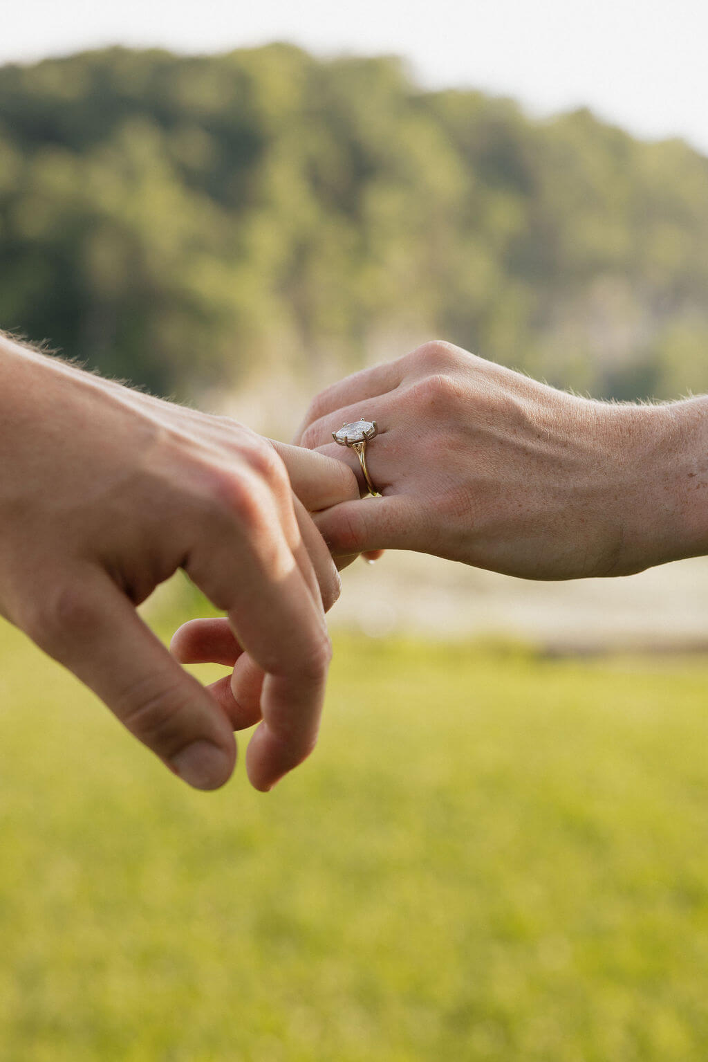 Close-up of an engagement ring as the couple gently reaches toward each other.