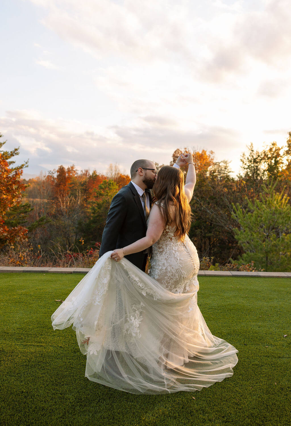 Newlyweds dance on the lawn with mountain views and orange foliage glowing behind them.