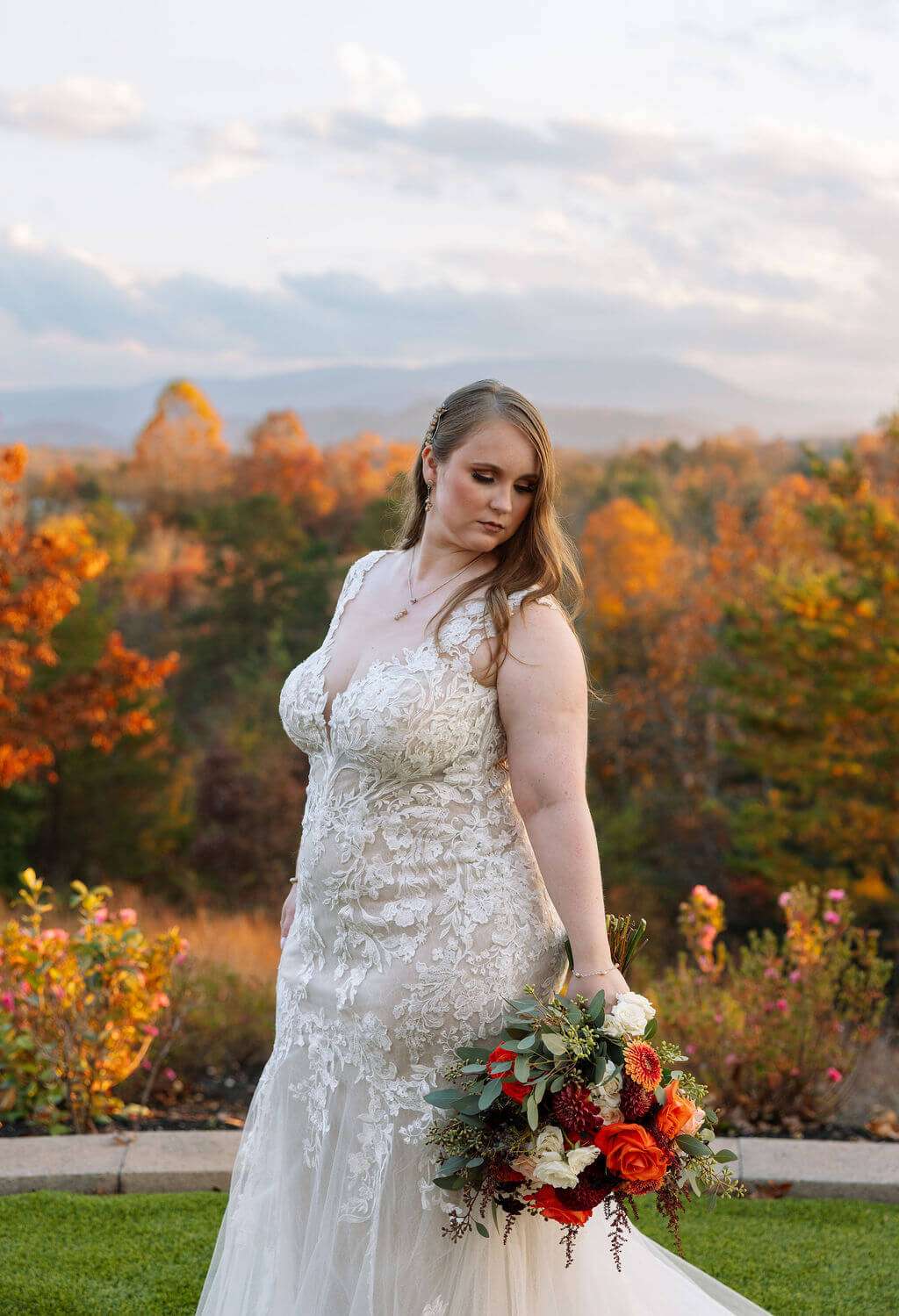Bride holds an autumn bouquet during a portrait with colorful Tennessee mountains and foliage behind her.