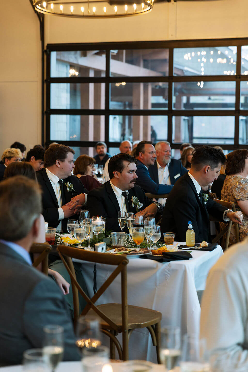 Wedding guests seated at round dinner tables inside a modern reception space.