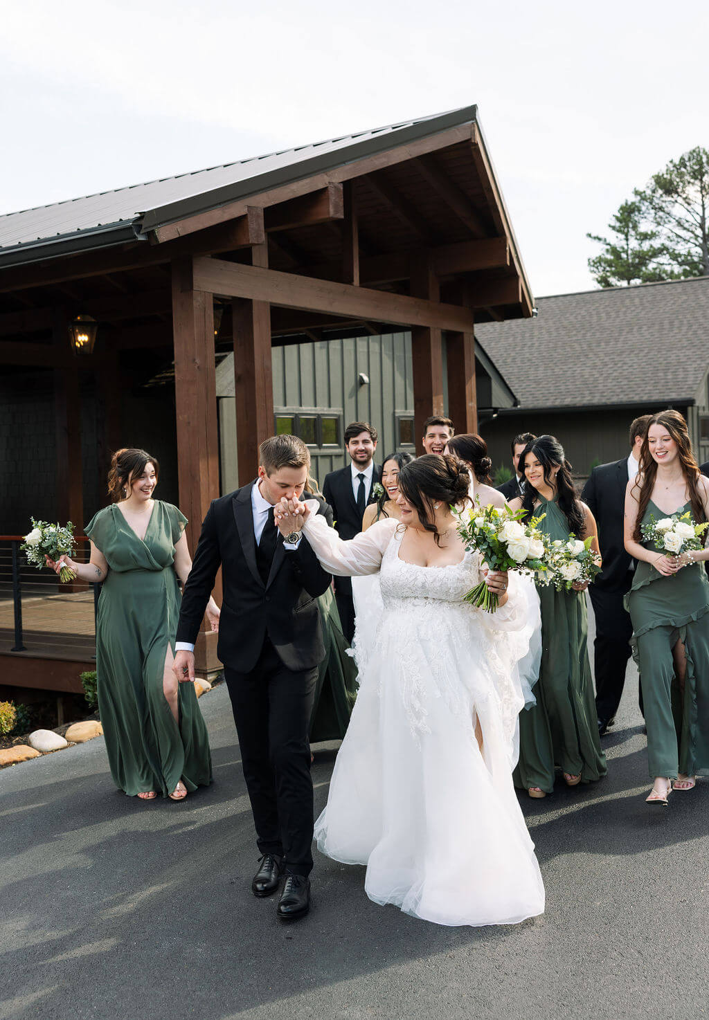 Newlyweds celebrating as their wedding party cheers outside a rustic mountain venue.