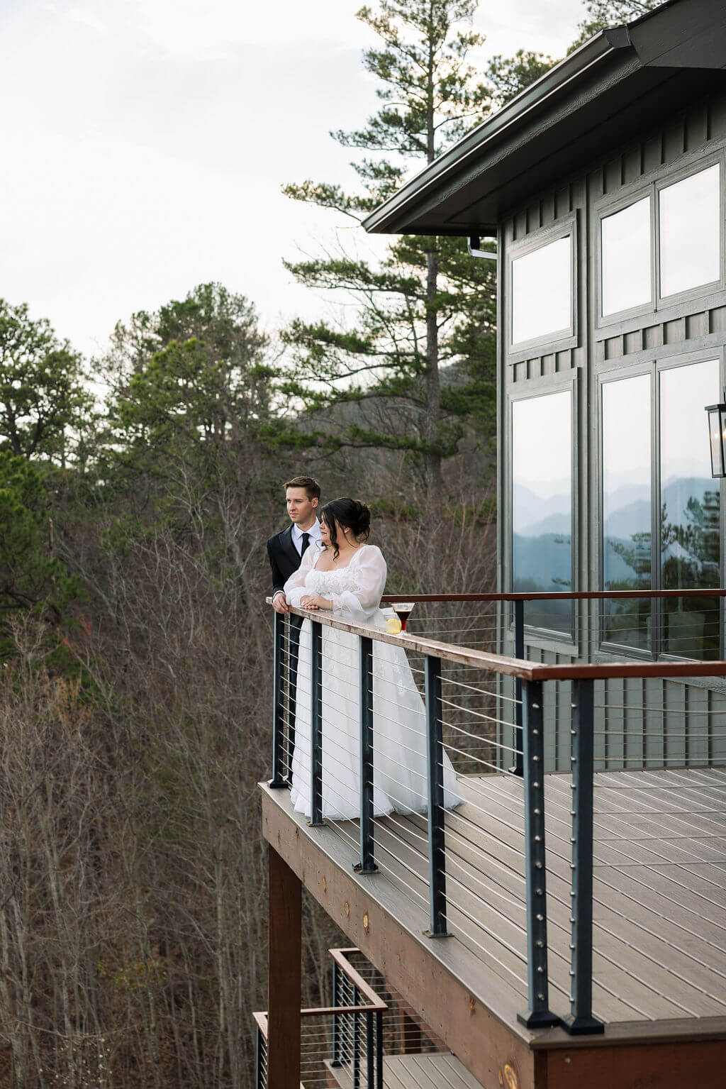 Newlyweds standing together on a balcony overlooking the surrounding Tennessee mountains.