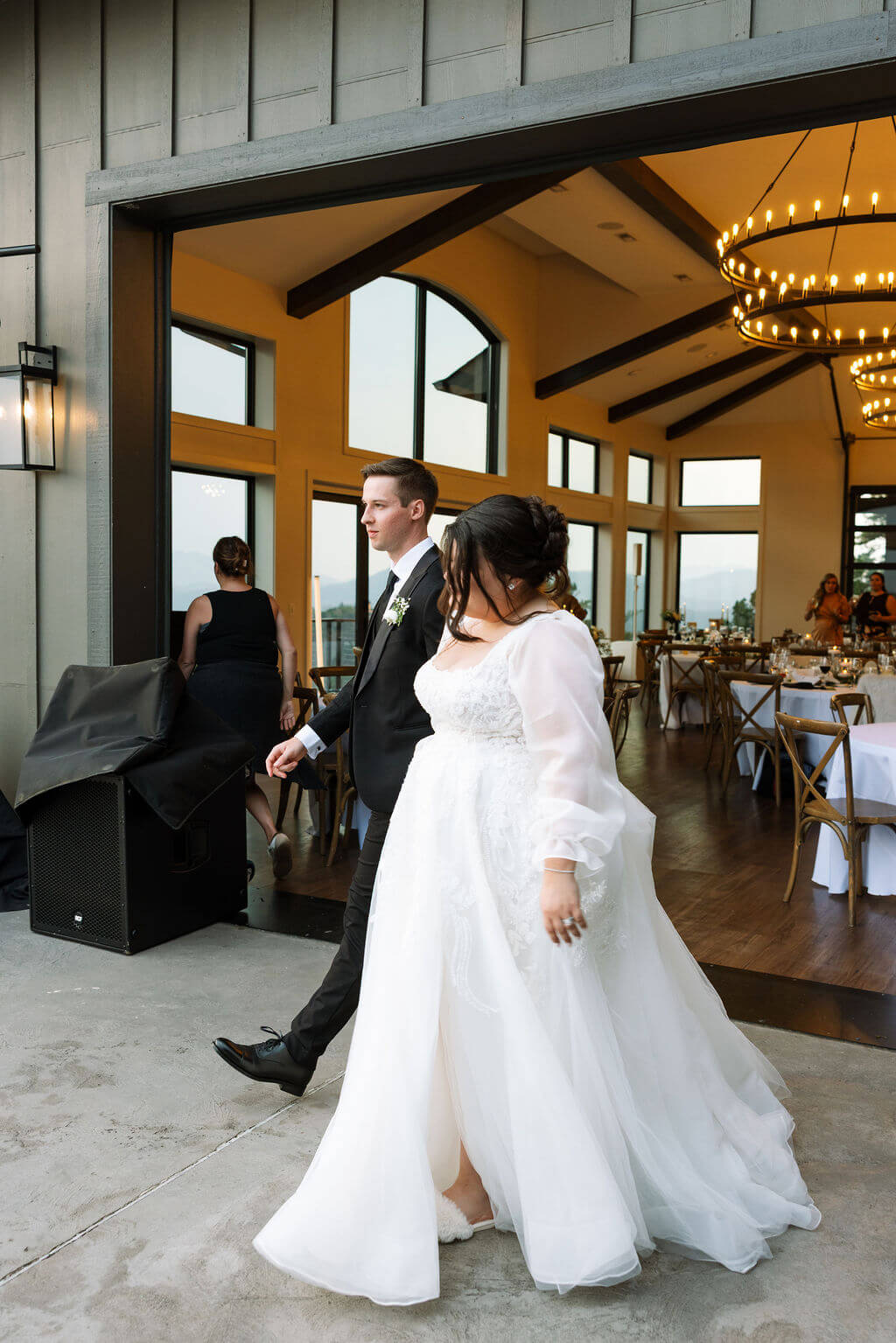 Bride and groom entering their reception through the doors of a modern mountain venue.