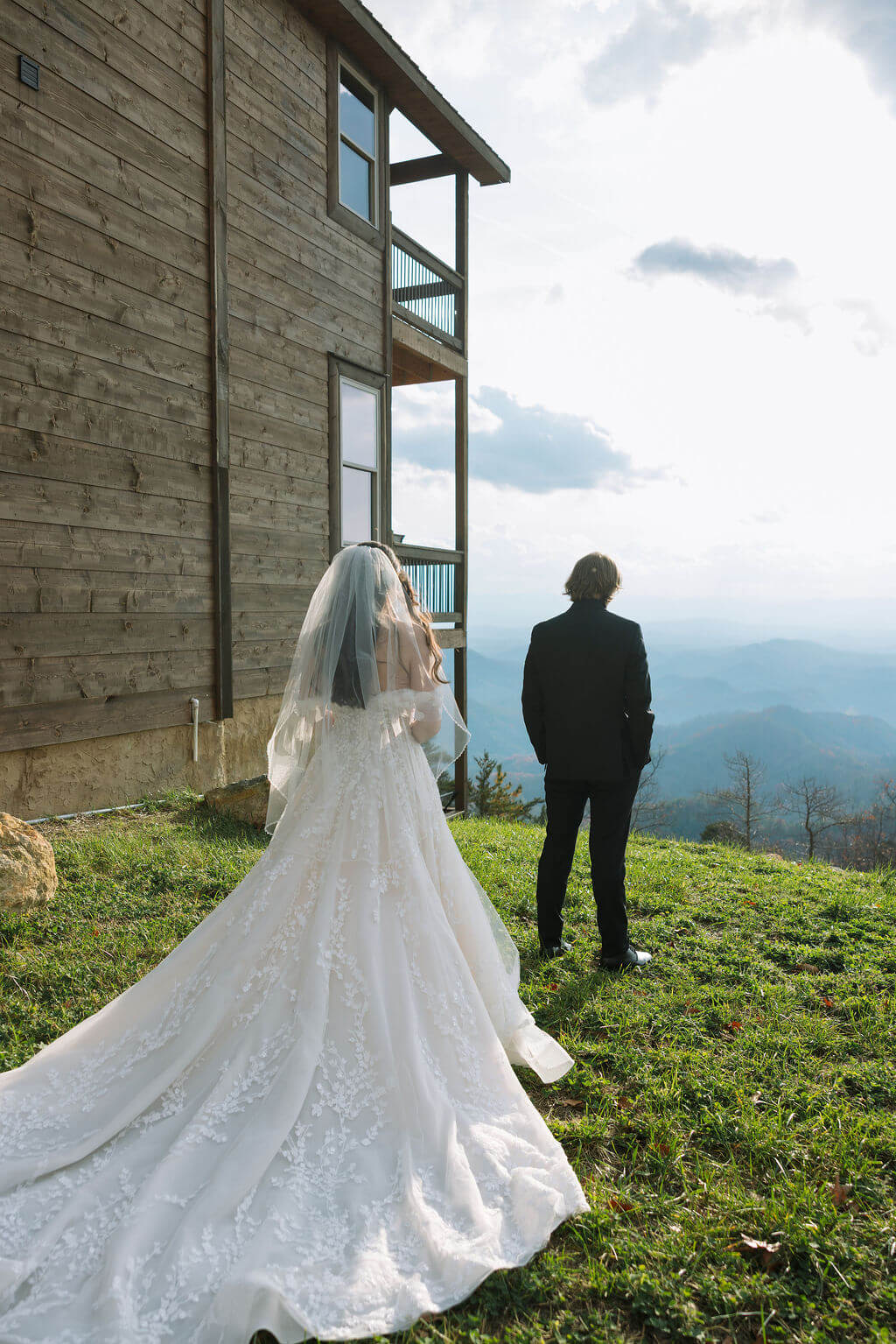 Bride approaches her partner for a first look outside a wooden mountain cabin overlooking the Smokies.